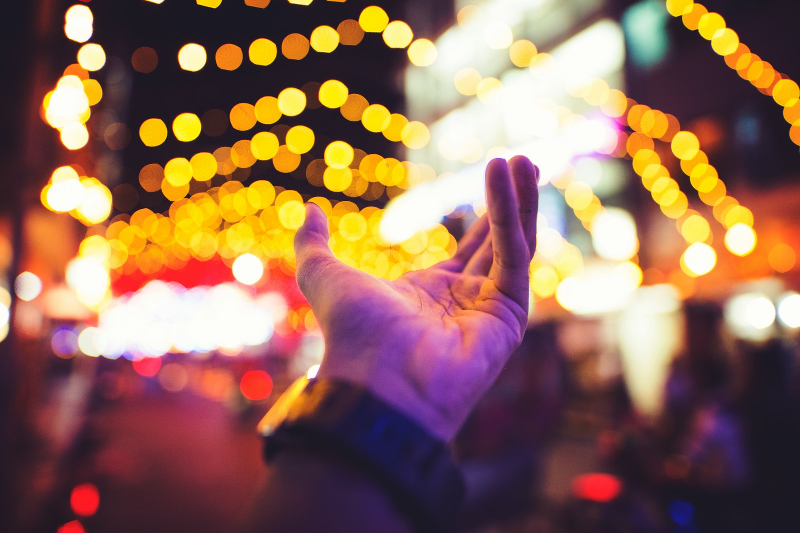 selective focus photography of person's left hand with yellow bokeh light background